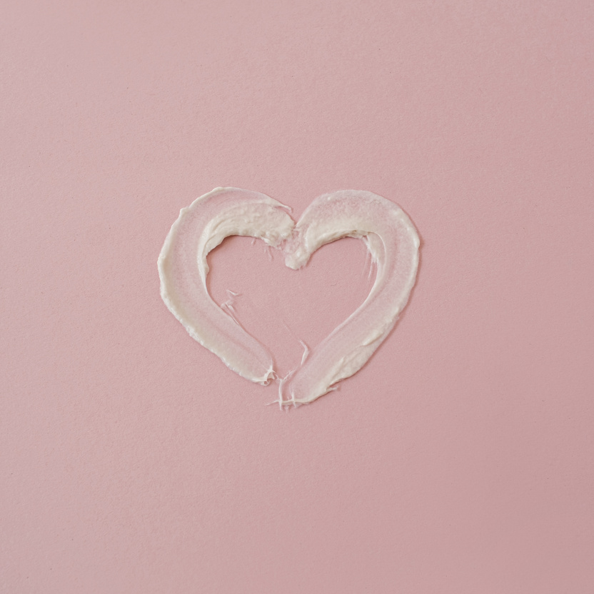 Cream Skincare Forming a Heart Shape on Pink Background 